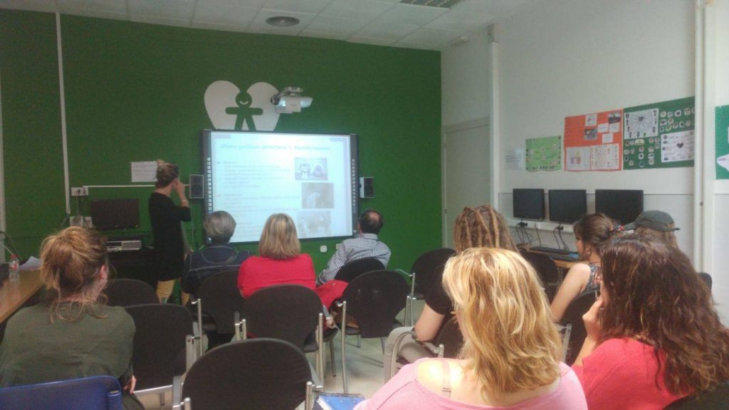 Imagen de profesionales, voluntariado y  familiares de socias/os de Bona Gent atendiendo durante la charla